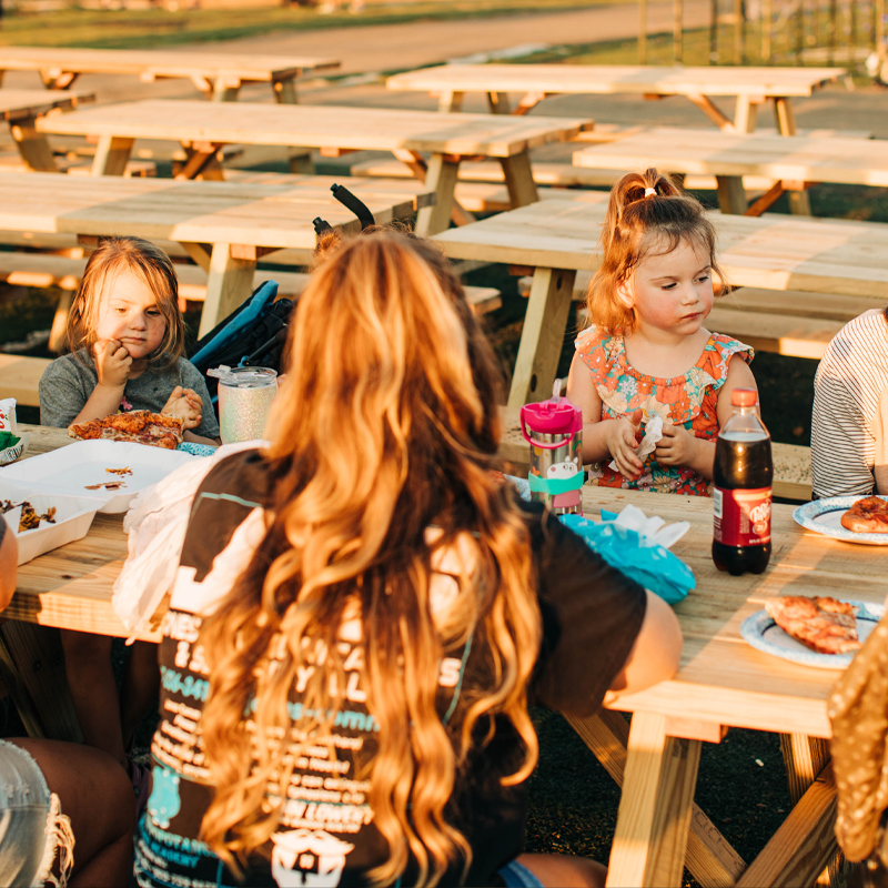 Guests Enjoy Food At Picnic Table